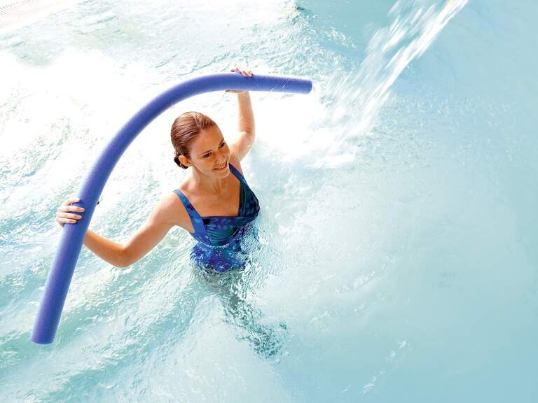 Eine junge Frau macht Wassergymnastik im Pool einer Therme von Bad Füssing.